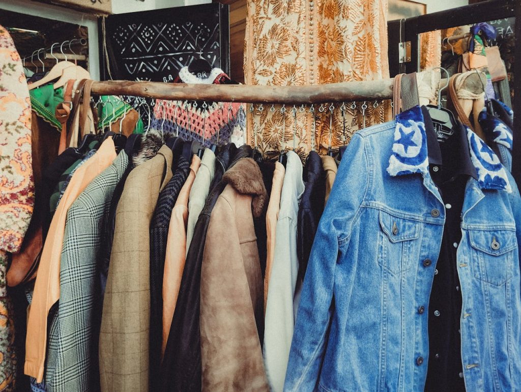 pexels-photo-31826316 A vibrant assortment of vintage jackets hanging on a wooden rack in a boutique.