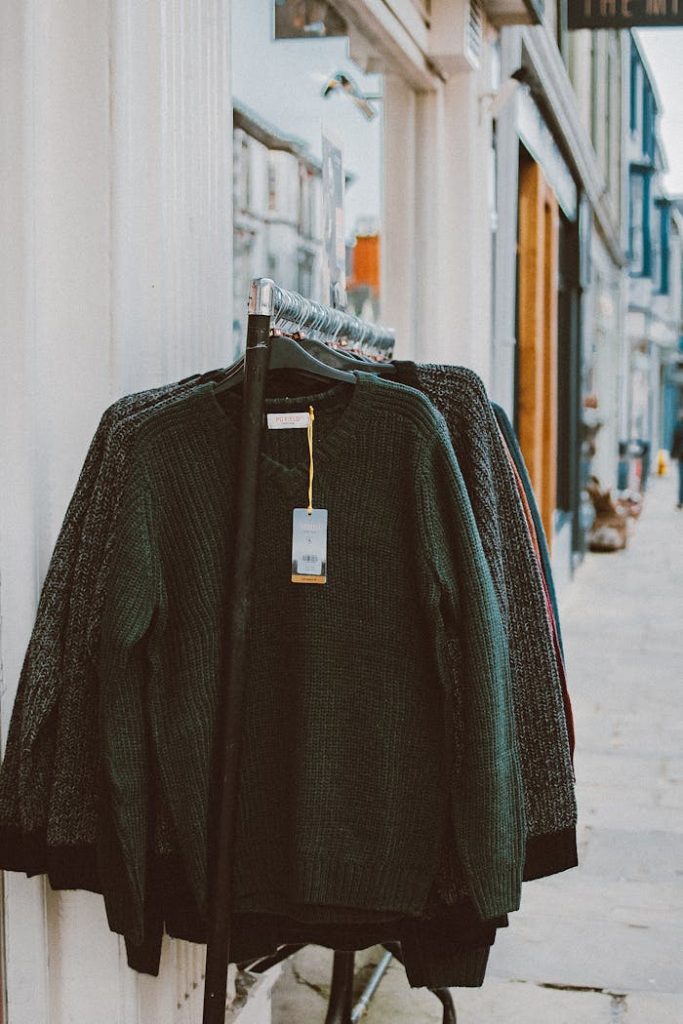 pexels-photo-3353621-1 Sweaters displayed on a clothing rack outside a shop, perfect for street shopping environments.